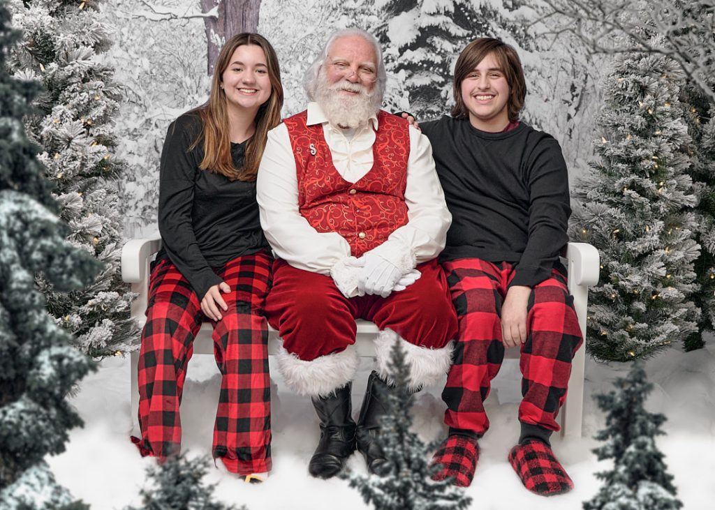 two teenagers sitting in the snow with Santa