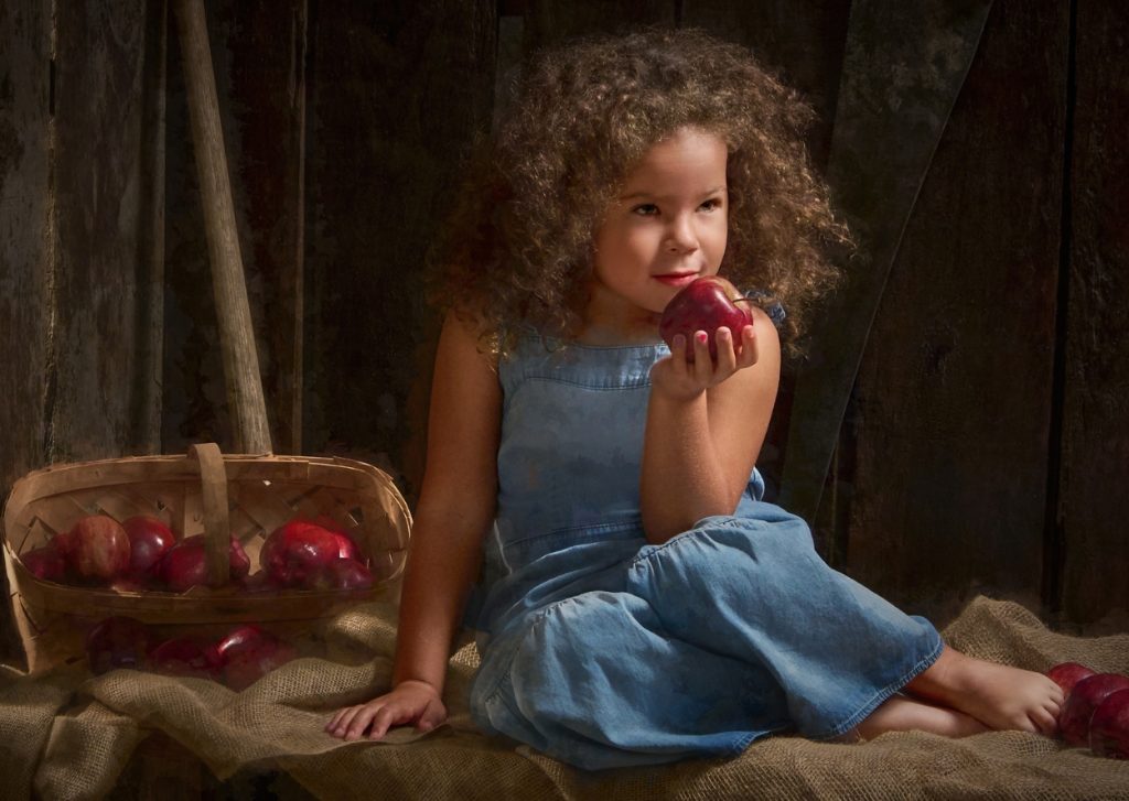Little girl with apples in a barn setting