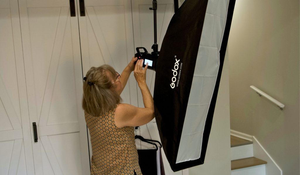 Photographer fine tuning a ceiling mounted light to keep the workflow efficient during a busy December schedule.