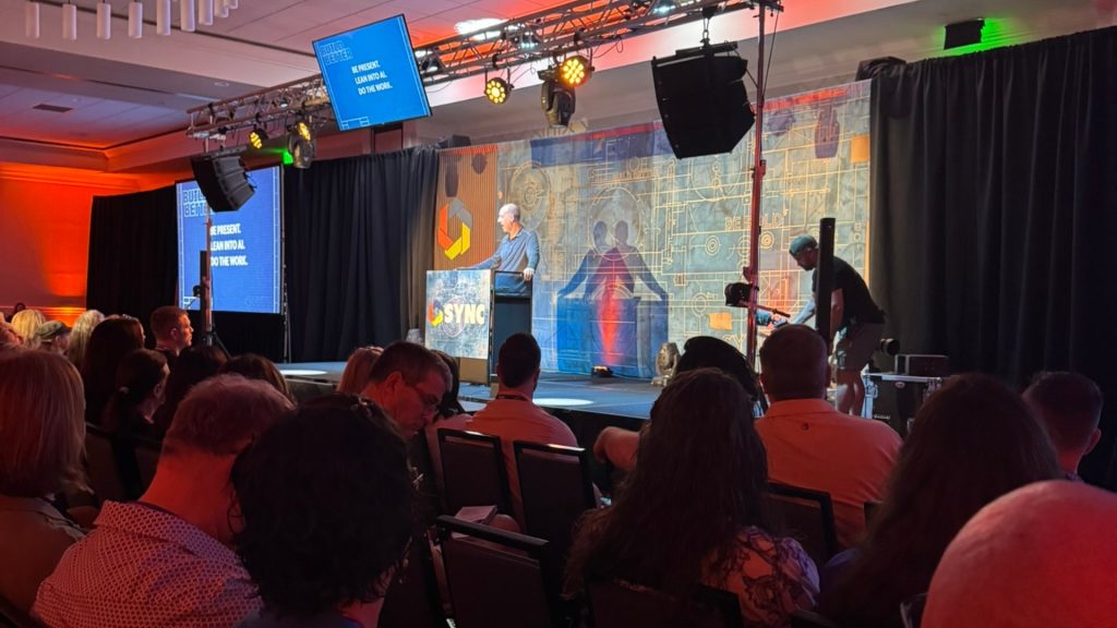 Intro to keynote speaker by conference organizer on stage at Sync 2026 photography conference in Destin Fl