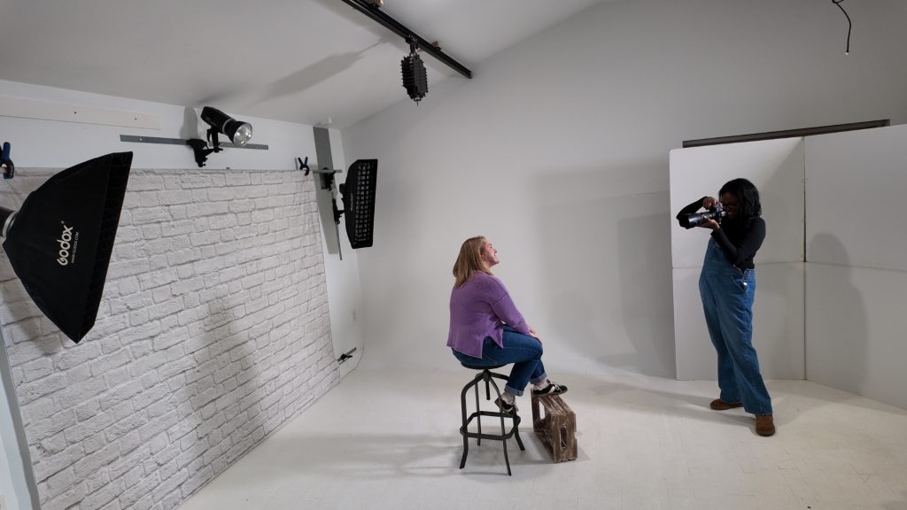 photographer shooting in organized studio with wall mounted backdrop and lighting system for consistent results