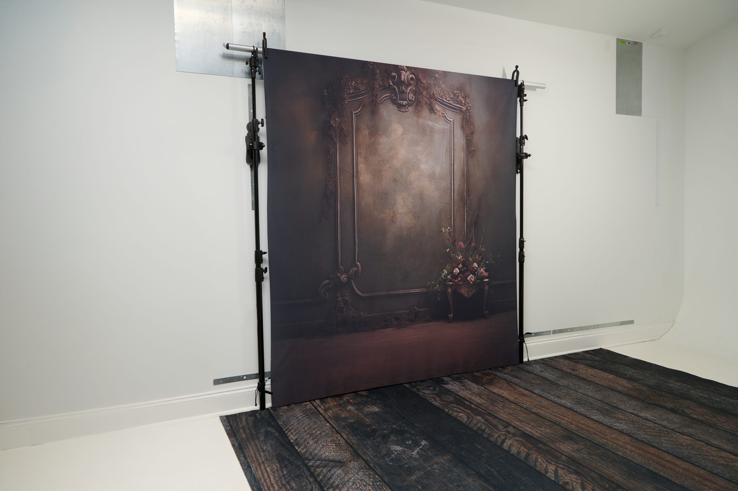 StandFree no-ladder backdrop system mounted on metal wall with adjustable extension rods raising backdrop