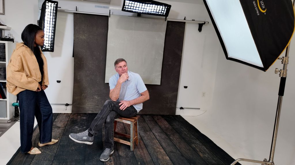 Photographer guiding relaxed client during portrait session in a calm photography studio environment