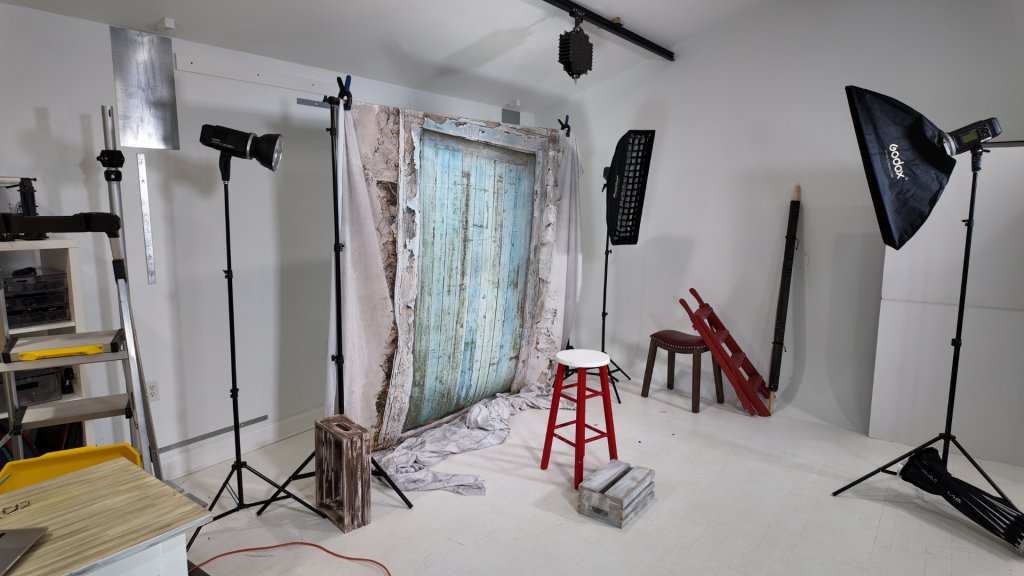 cluttered photography studio with multiple stands and backdrops taking up space