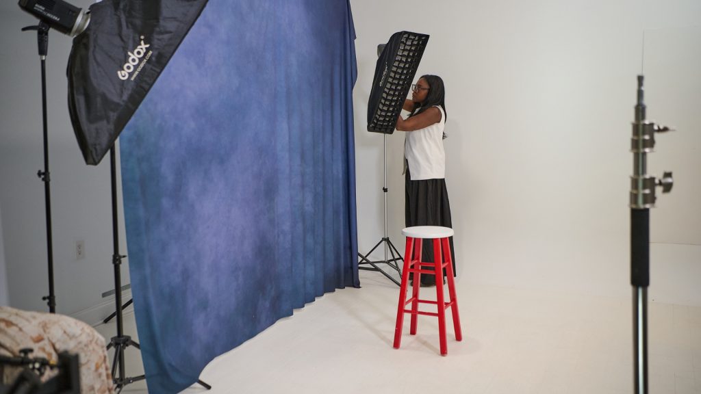 photographer struggling with cluttered studio and backdrop stands