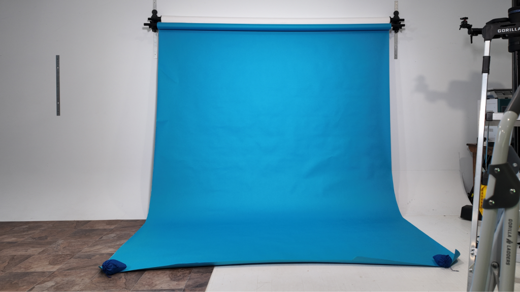 Blue photography backdrop mounted in an organized studio setup designed for efficient photography workflow