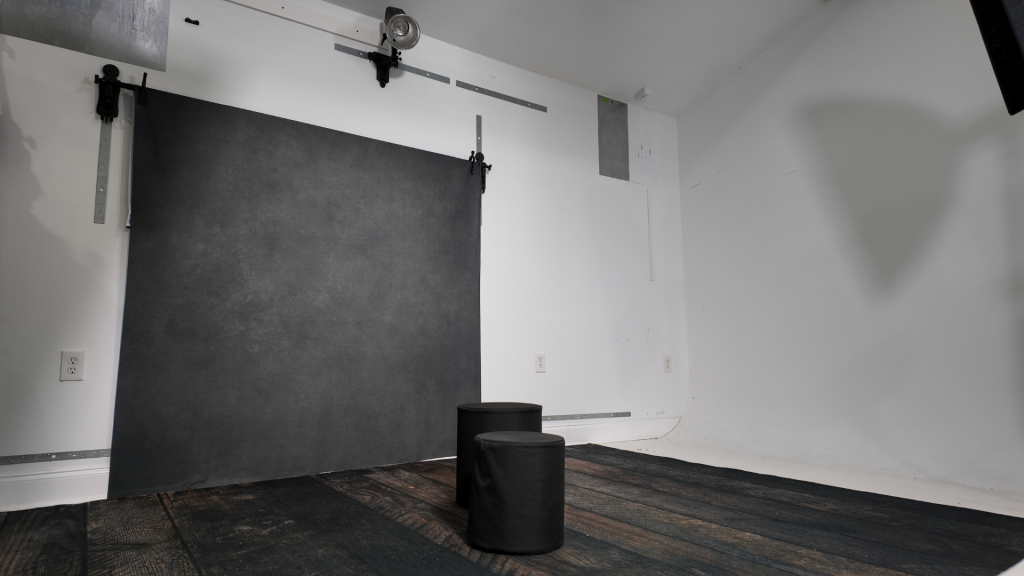 Clean photography studio with wall-mounted backdrop system and open floor space