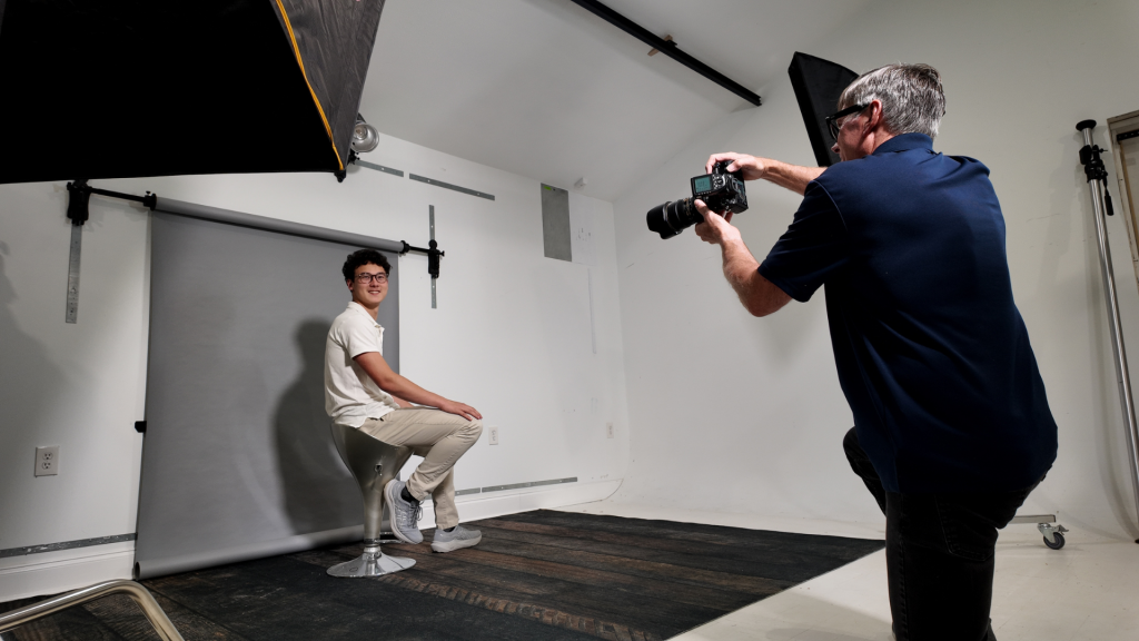 Photographer using a wall-mounted backdrop system in a small studio space