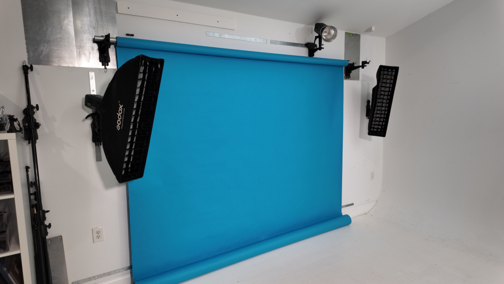 Organized photography studio with seamless backdrop and wall-mounted lighting