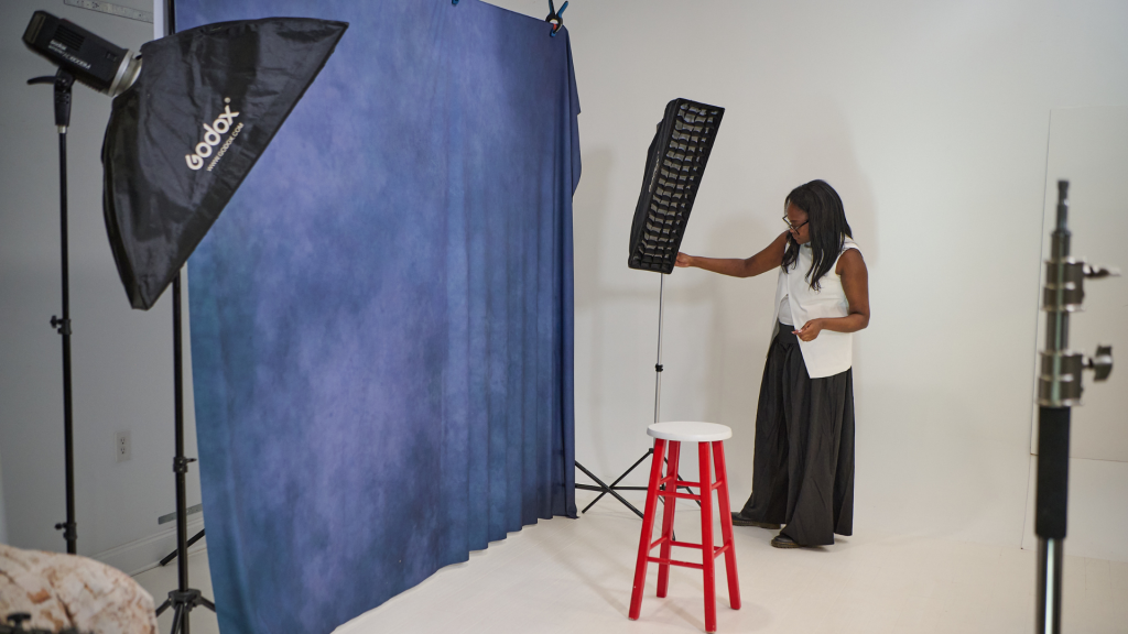 Photography studio with blue backdrop, light stands, and modifiers set up in a small space