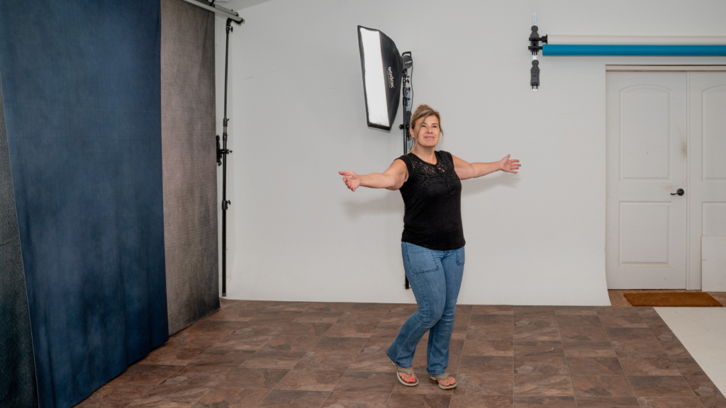 Photographer demonstrating reclaimed studio space with integrated wall mounted lighting and backdrop system