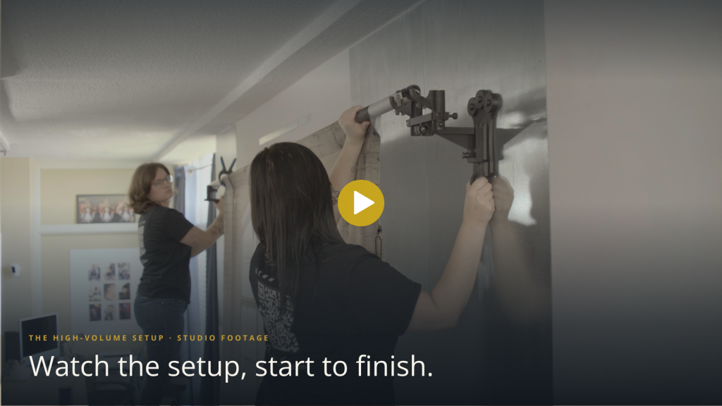 Studio setup demonstration showing a photographer changing backdrops on a wall-mounted photography system.