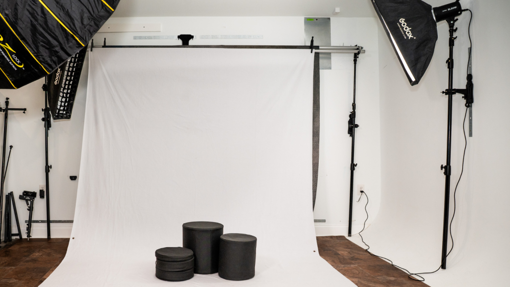 Photography studio with wall mounted lighting and backdrop system creating a clear shooting area